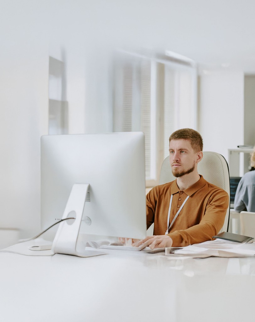 Person arbeitet an einem großen Bildschirm in einem hellen Büro.