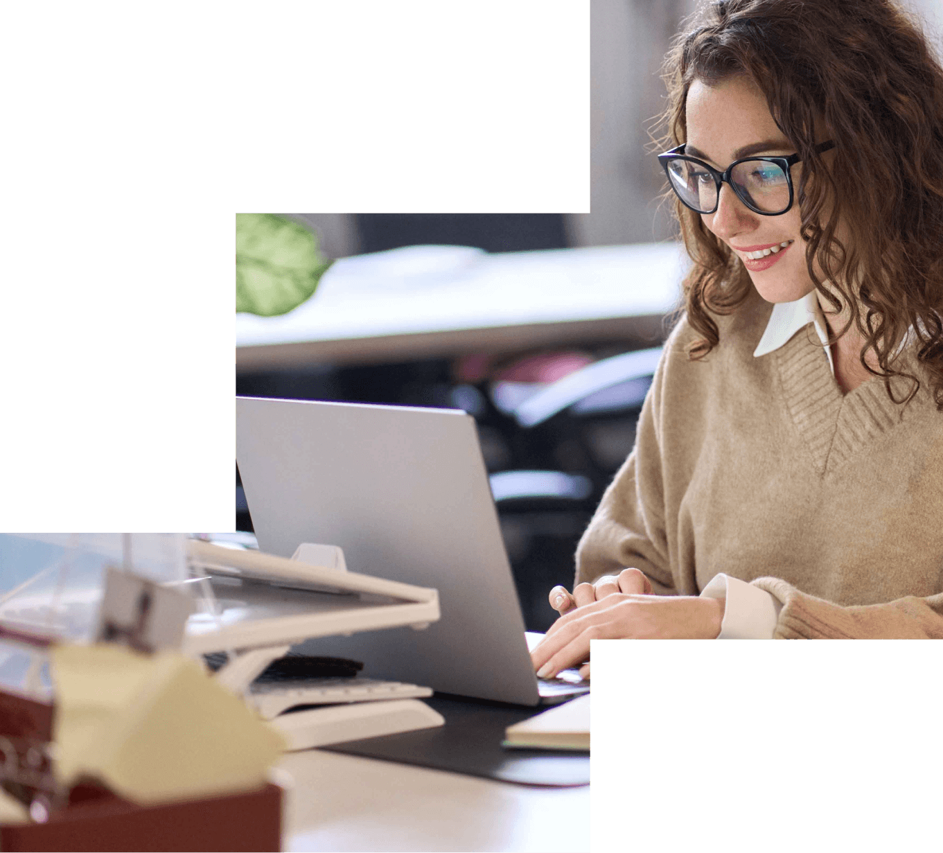 Lächelnde Person mit Brille arbeitet an einem Laptop in einem hellen Büro.